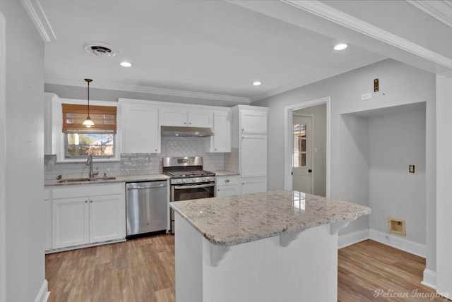 kitchen featuring visible vents, a sink, under cabinet range hood, stainless steel appliances, and light wood finished floors