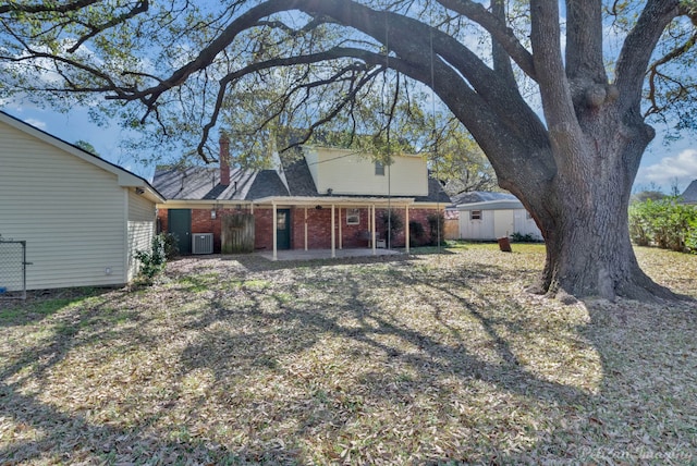 back of property with brick siding, a patio area, central AC unit, an outbuilding, and a storage unit