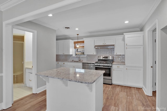 kitchen with under cabinet range hood, stainless steel appliances, crown molding, and a sink