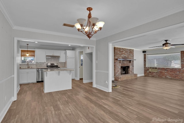 kitchen featuring open floor plan, ornamental molding, appliances with stainless steel finishes, wood finished floors, and white cabinets