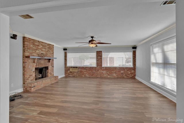 unfurnished living room with visible vents, ornamental molding, wood finished floors, brick wall, and ceiling fan