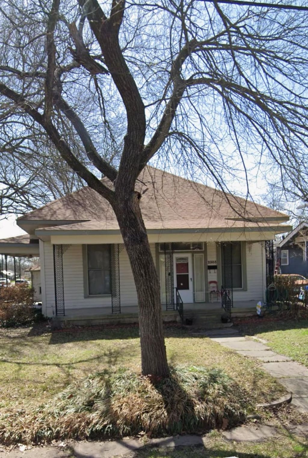 view of front facade featuring roof with shingles, covered porch, and a front yard