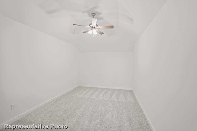 spare room with lofted ceiling, light carpet, baseboards, and ceiling fan