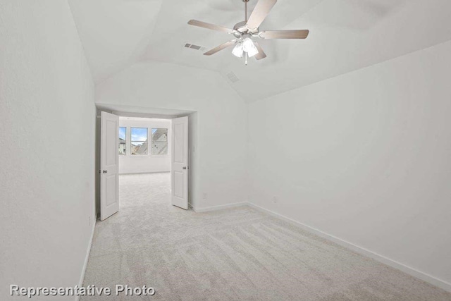 empty room featuring visible vents, baseboards, ceiling fan, light colored carpet, and vaulted ceiling