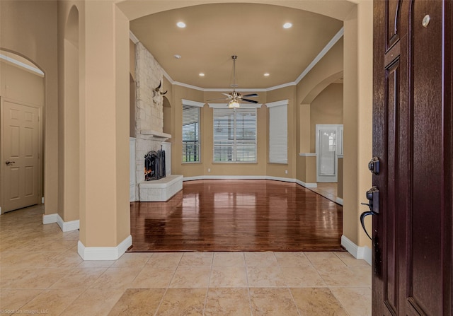 477 Horseshoe Bnd, Royse City, TX 75189 - foyer entrance featuring ornamental molding, ceiling fan, a stone fireplace, arched walkways, and light tile patterned floors