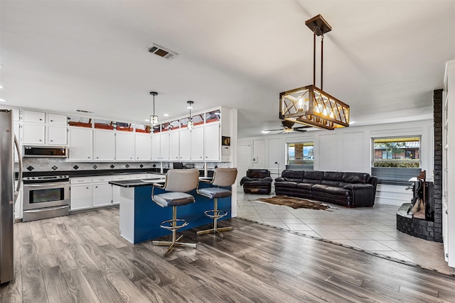 101 Hill Top Cir, Burleson, TX 76028 - kitchen featuring white cabinets, dark countertops, visible vents, wood finished floors, and appliances with stainless steel finishes