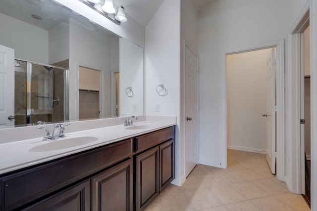 bathroom featuring a stall shower, double vanity, a sink, and tile patterned floors