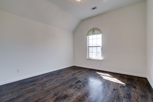empty room featuring visible vents, baseboards, lofted ceiling, and dark wood-style floors