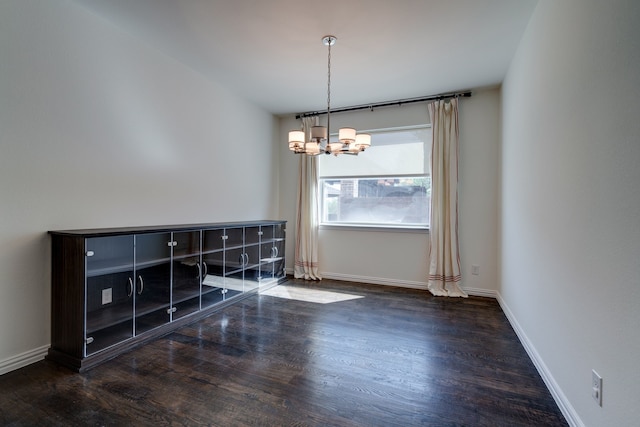 unfurnished dining area featuring wood finished floors, a notable chandelier, and baseboards