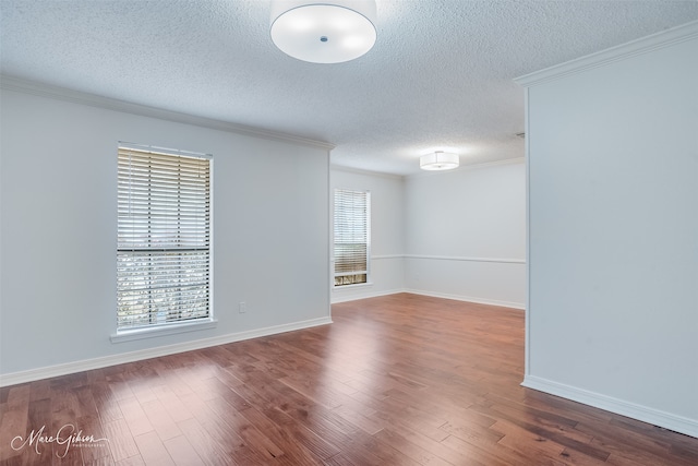 spare room featuring crown molding, baseboards, a textured ceiling, and wood finished floors