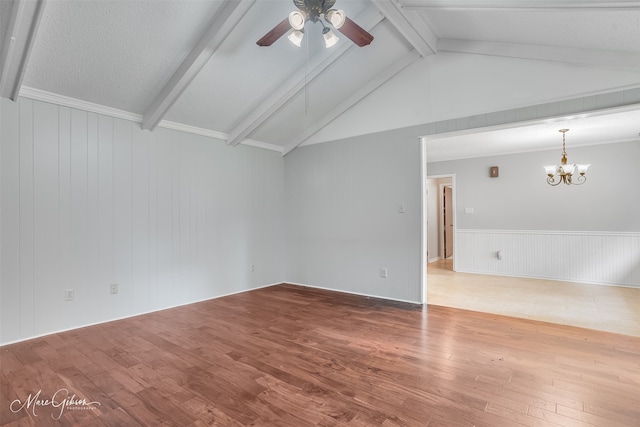 unfurnished room with vaulted ceiling with beams, ceiling fan with notable chandelier, wood finished floors, and a wainscoted wall