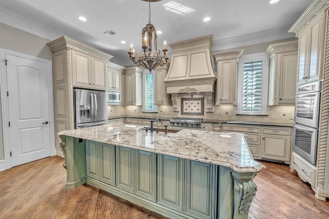 2909 Canyon Creek Dr, Sherman, TX 75092 - kitchen featuring appliances with stainless steel finishes, cream cabinets, a chandelier, wall chimney exhaust hood, and recessed lighting