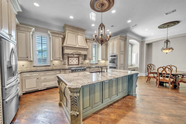 2909 Canyon Creek Dr, Sherman, TX 75092 - kitchen with appliances with stainless steel finishes, cream cabinets, wall chimney exhaust hood, arched walkways, and light stone countertops