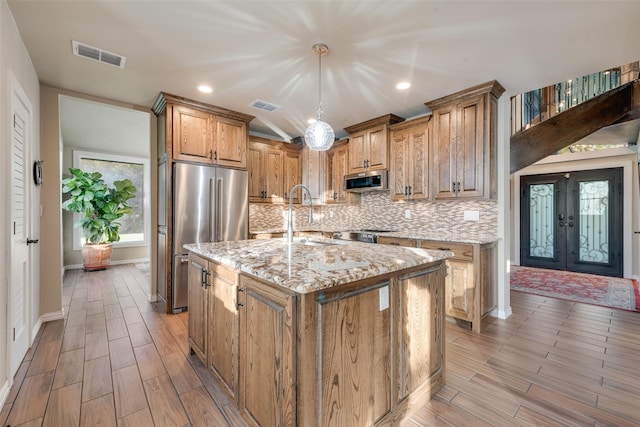 kitchen featuring a sink, visible vents, appliances with stainless steel finishes, and light stone countertops