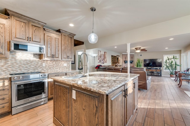 kitchen featuring open floor plan, backsplash, appliances with stainless steel finishes, and light wood finished floors