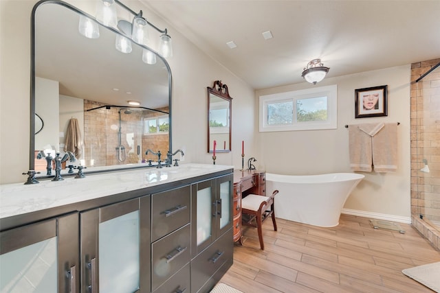 full bath with double vanity, a shower stall, a freestanding bath, a sink, and wood finished floors