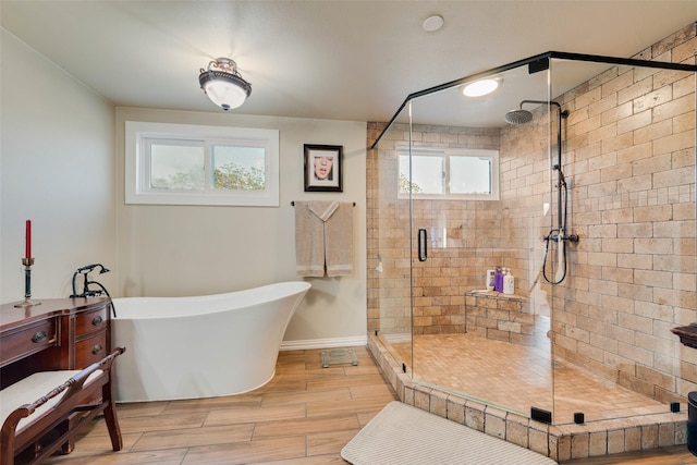 bathroom featuring baseboards, wood tiled floor, a stall shower, and a soaking tub