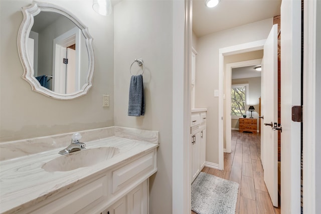 bathroom with baseboards, vanity, and wood finished floors
