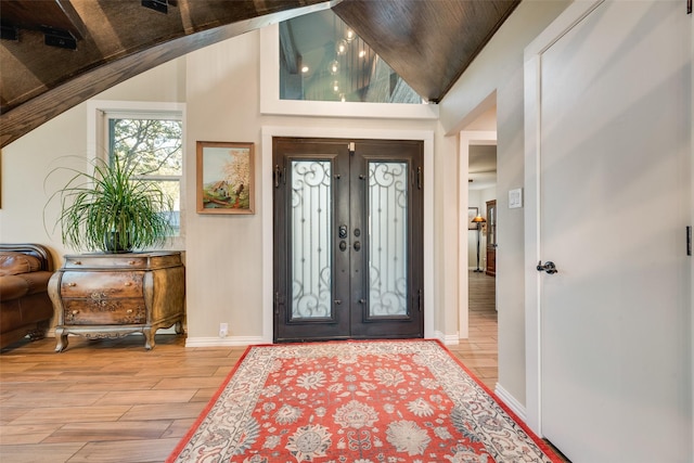 foyer entrance with light wood-style flooring, vaulted ceiling, and baseboards