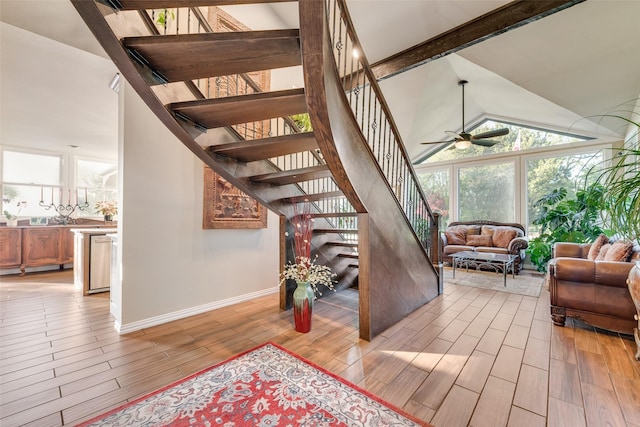 stairs with high vaulted ceiling, ceiling fan, wood tiled floor, baseboards, and beam ceiling