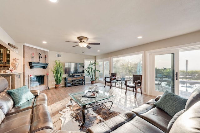 living area featuring a fireplace, a ceiling fan, visible vents, recessed lighting, and light wood finished floors