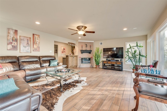 living room featuring light wood-style flooring, a fireplace, a ceiling fan, and recessed lighting