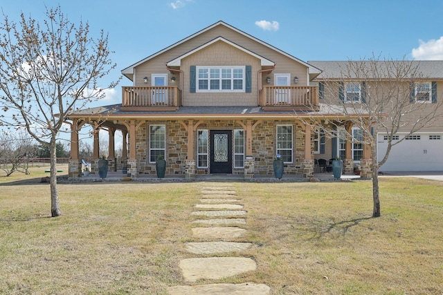 view of front facade featuring an attached garage, stone siding, a balcony, a front yard, and covered porch