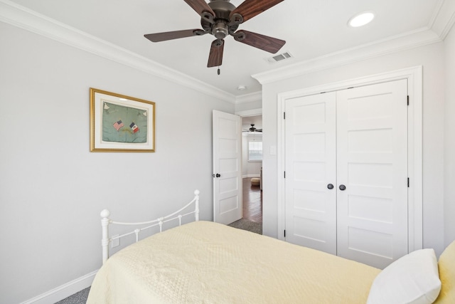 carpeted bedroom with crown molding, baseboards, visible vents, a ceiling fan, and a closet