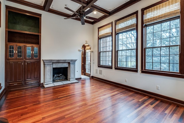 unfurnished living room with a ceiling fan, plenty of natural light, wood finished floors, and a fireplace