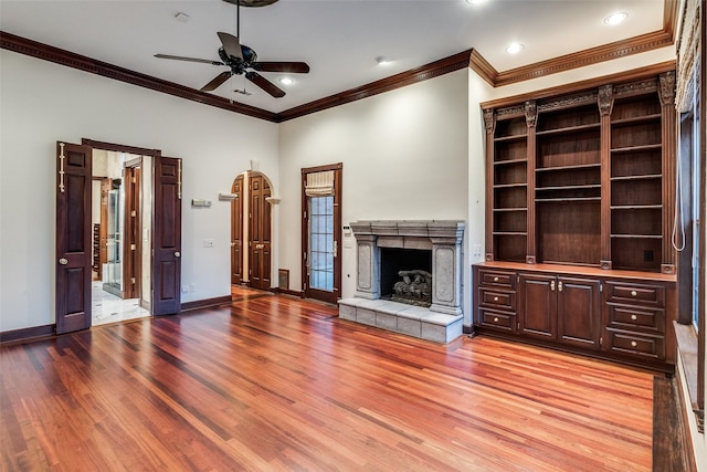 unfurnished living room with ceiling fan, ornamental molding, light wood finished floors, and a fireplace