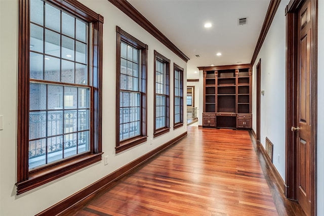 hallway featuring crown molding, recessed lighting, baseboards, wood finished floors, and visible vents