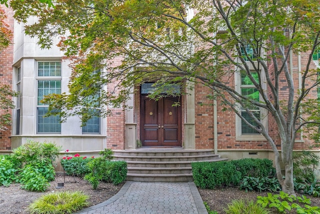 entrance to property featuring brick siding and crawl space