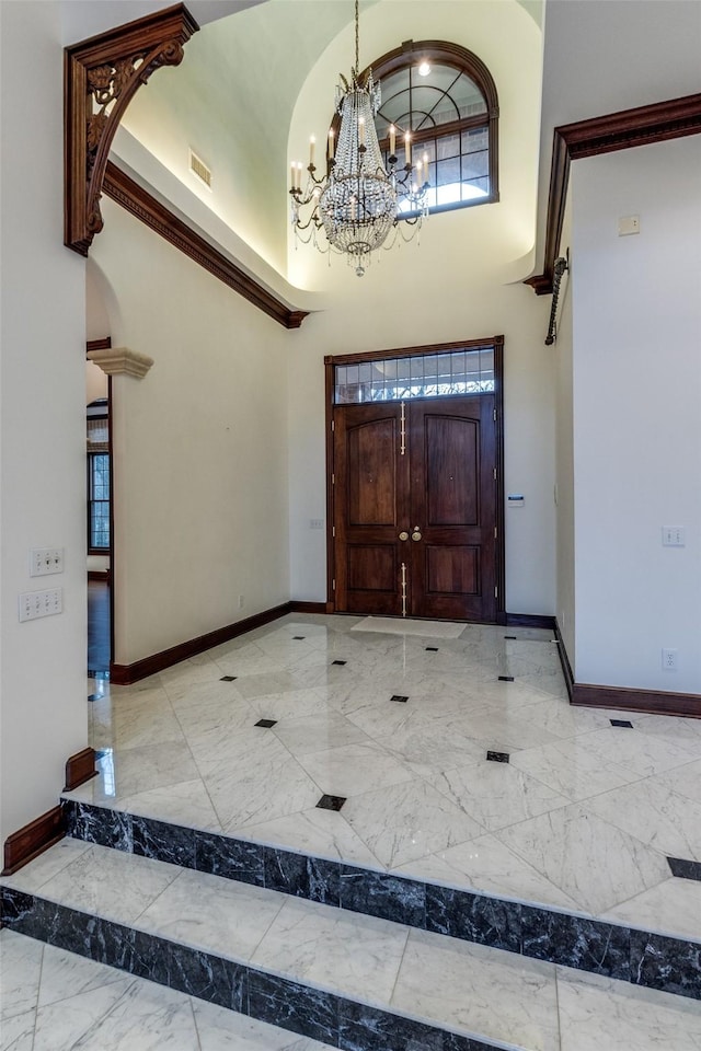 entrance foyer with visible vents, marble finish floor, baseboards, a high ceiling, and a notable chandelier