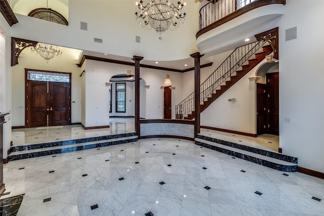entrance foyer featuring a high ceiling, a notable chandelier, baseboards, and marble finish floor