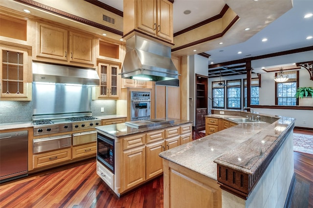kitchen featuring a warming drawer, ornamental molding, a large island with sink, and island exhaust hood