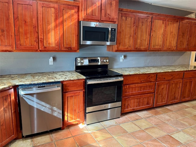 kitchen featuring light stone counters, light tile patterned flooring, brown cabinets, and stainless steel appliances