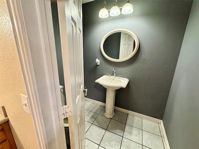 bathroom with tile patterned floors, baseboards, and a textured wall