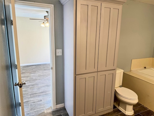 bathroom with baseboards, a ceiling fan, wood tiled floor, and toilet