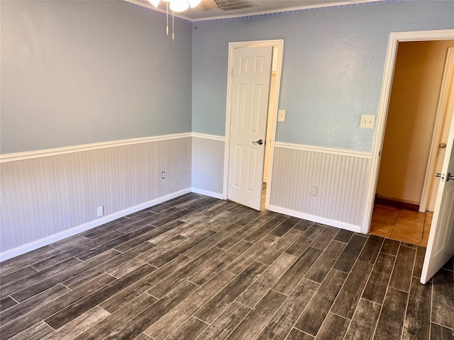 unfurnished bedroom with wood finish floors, visible vents, and wainscoting