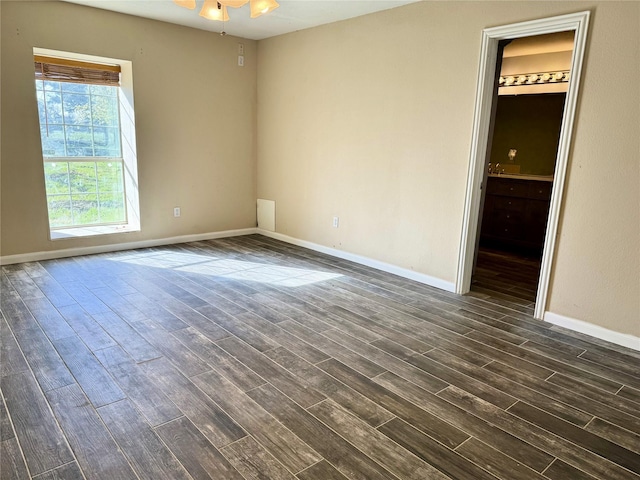 unfurnished room featuring dark wood-style floors, a ceiling fan, and baseboards