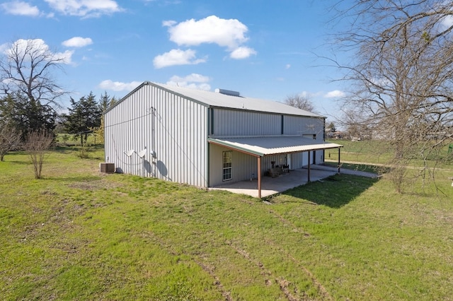 back of house with metal roof, a lawn, and a pole building