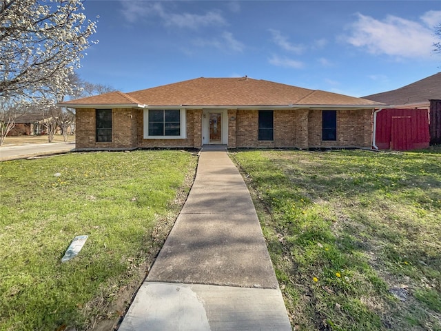 ranch-style house featuring a front yard, brick siding, and roof with shingles