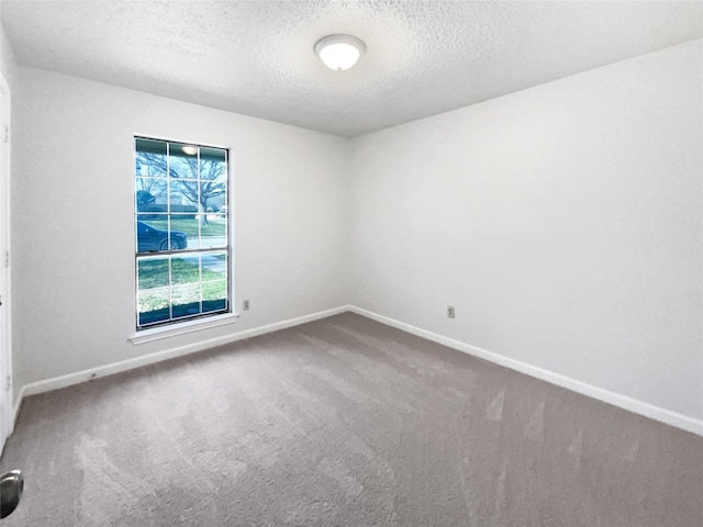 unfurnished room with carpet flooring, baseboards, and a textured ceiling