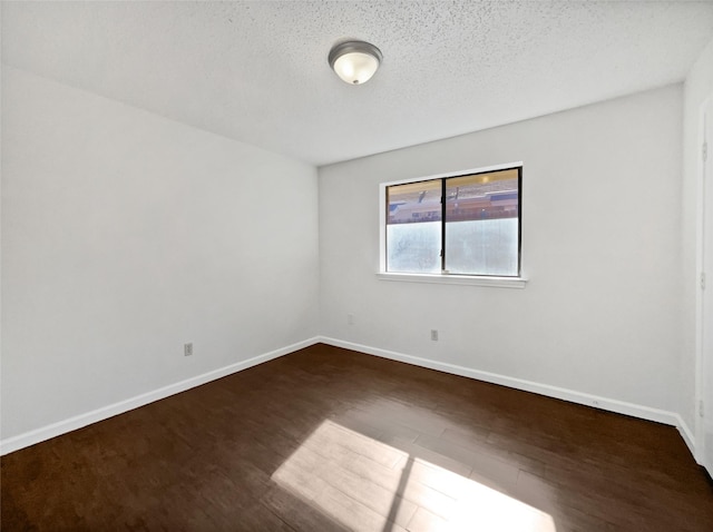 empty room featuring baseboards, a textured ceiling, and dark wood finished floors