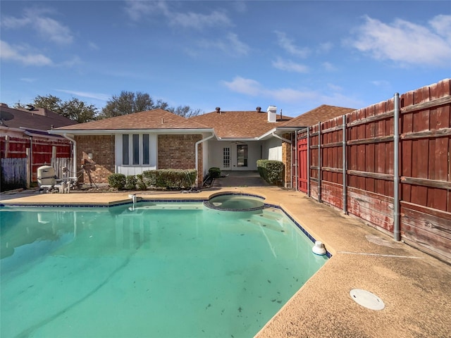 view of pool with a pool with connected hot tub, a patio, and fence