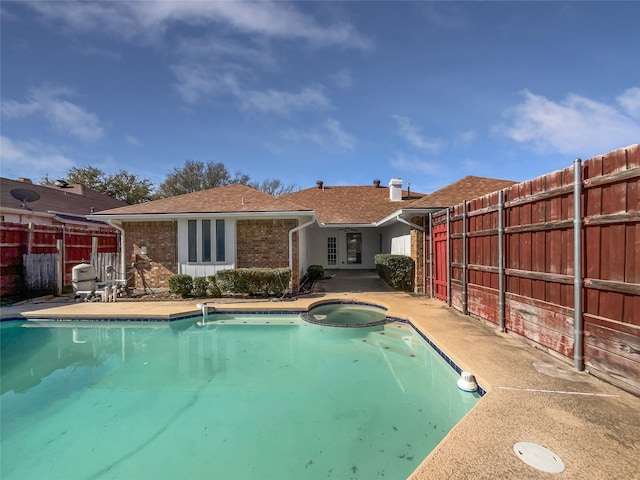 view of swimming pool with a patio area, fence, and a pool with connected hot tub