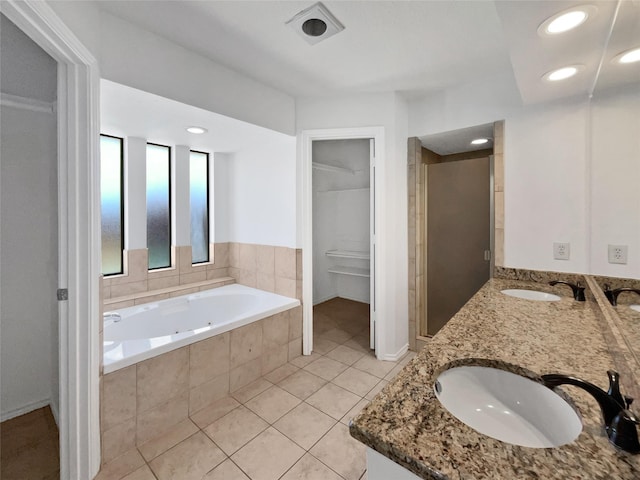 bathroom featuring a bath, tile patterned floors, a spacious closet, and a sink