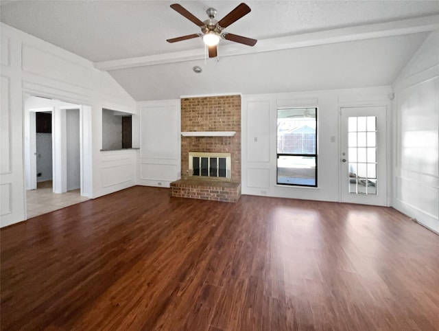 unfurnished living room featuring a decorative wall, lofted ceiling with beams, ceiling fan, and wood finished floors
