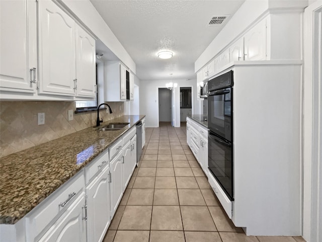 kitchen featuring visible vents, backsplash, dishwasher, white cabinetry, and a sink