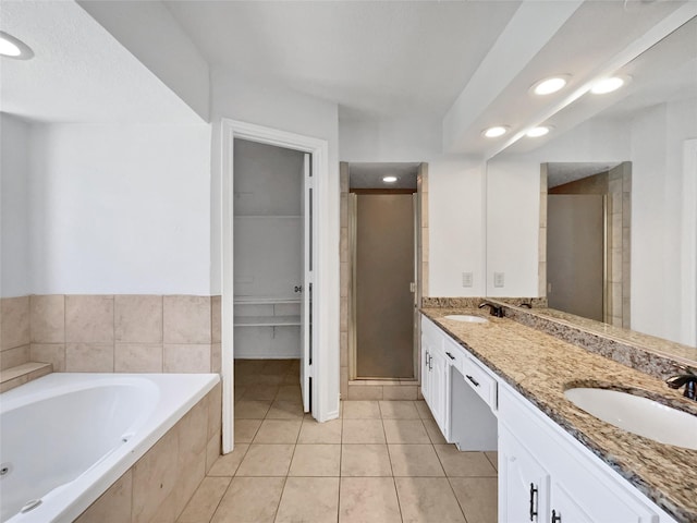bathroom with double vanity, a stall shower, tile patterned floors, a tub with jets, and a sink